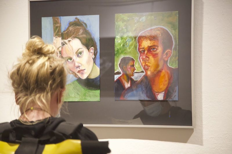 Besucherin vor Gemälden in einer Ausstellung